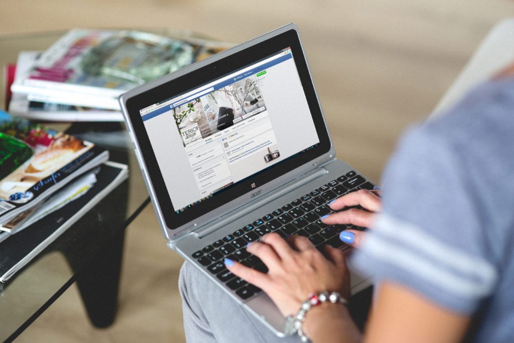 Mulher digitando no Facebook em laptop